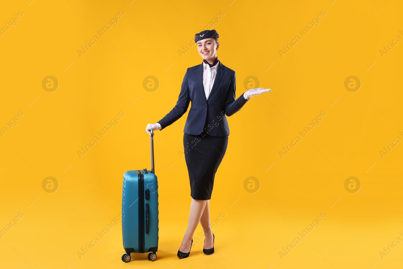 Photo of Positive stewardess with suitcase on yellow background