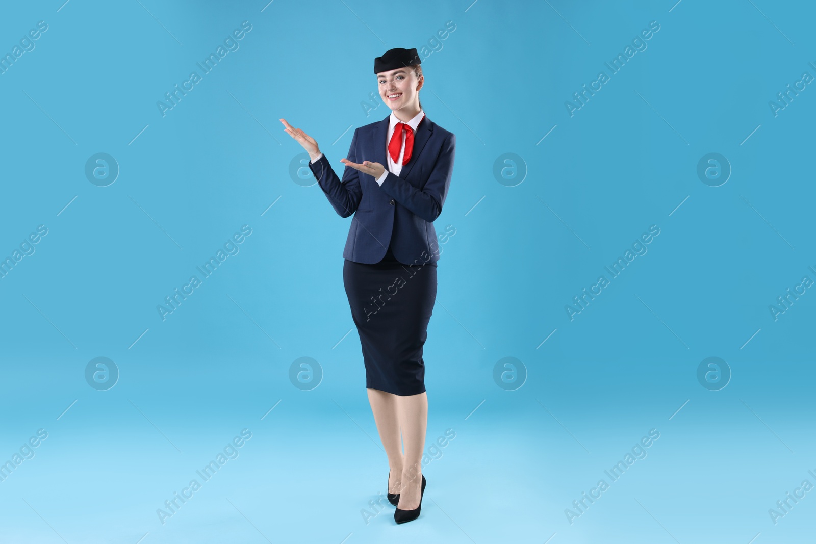 Photo of Beautiful stewardess showing something on light blue background