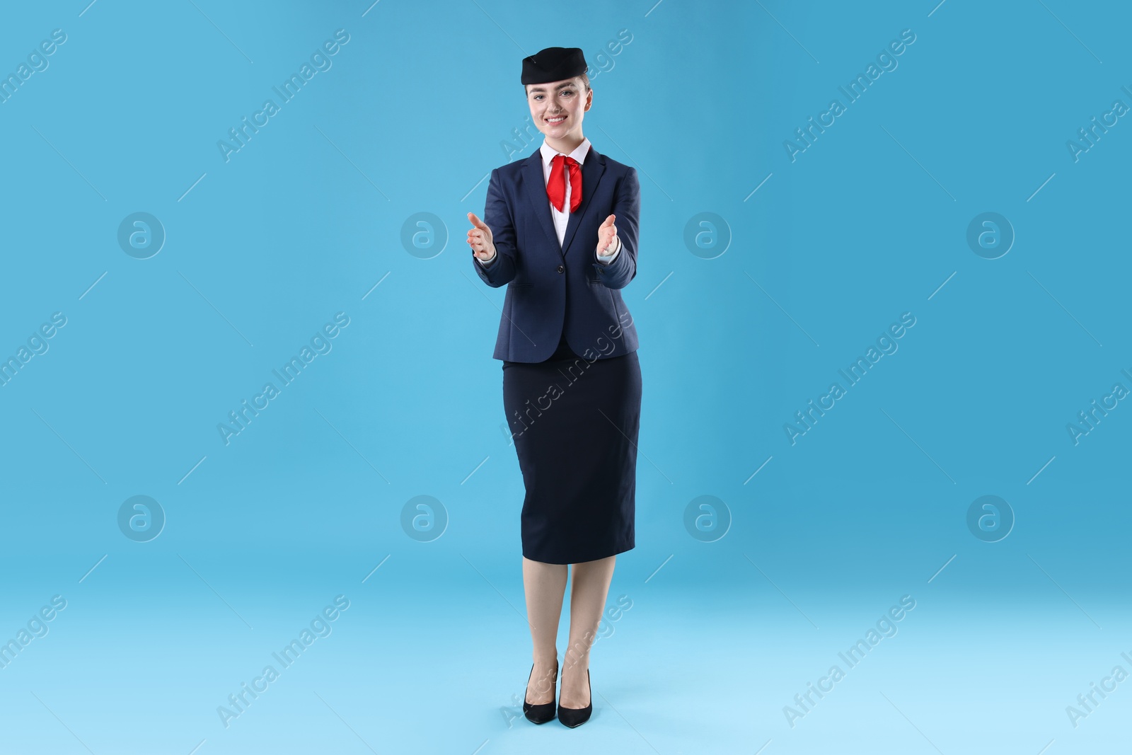 Photo of Positive stewardess doing pre-flight safety briefing on light blue background