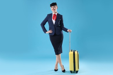 Photo of Positive stewardess with suitcase on light blue background