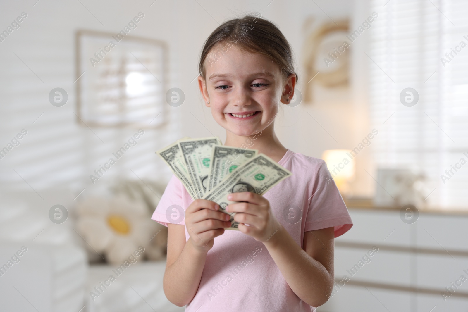 Photo of Little girl holding pocket money at home