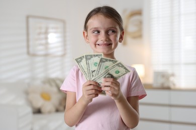 Photo of Little girl holding pocket money at home