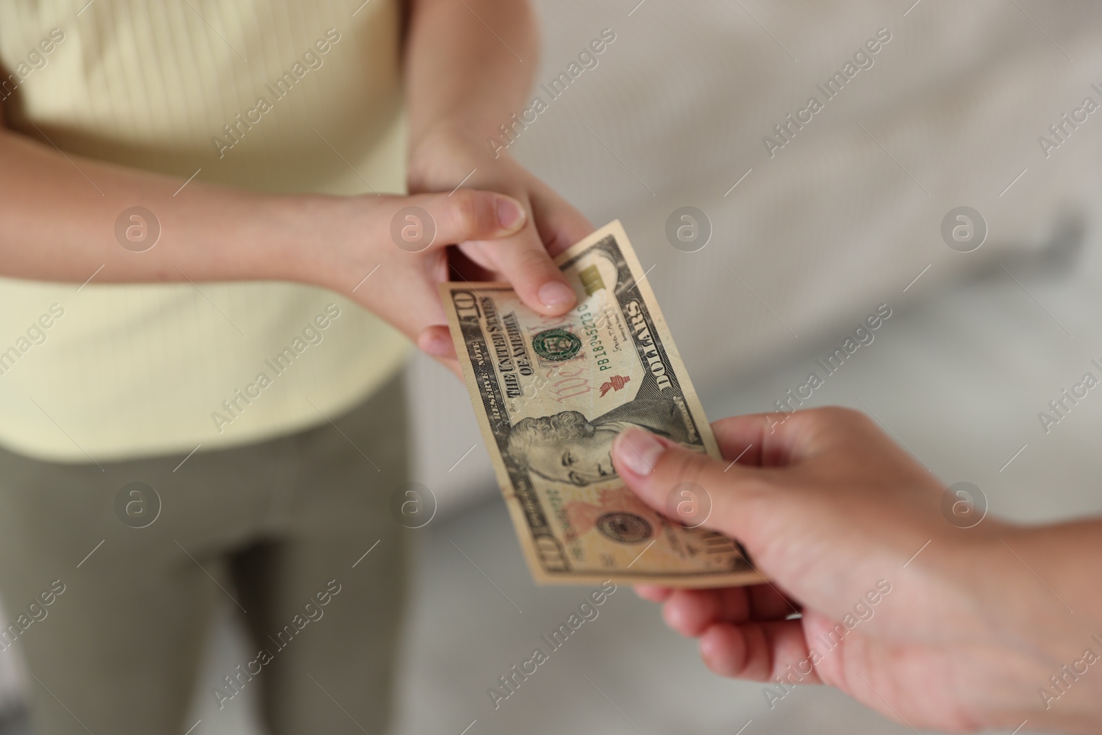 Photo of Mother giving pocket money to her daughter at home, closeup