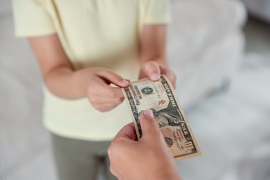 Photo of Mother giving pocket money to her daughter at home, closeup