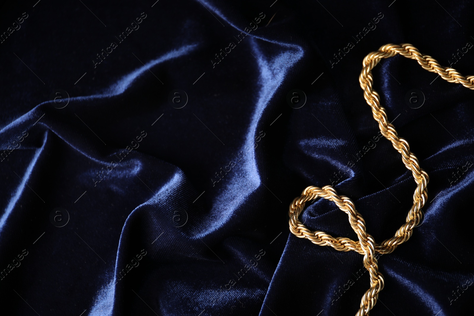 Photo of Stylish gold necklace on blue silk cloth, top view. Space for text