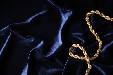 Photo of Stylish gold necklace on blue silk cloth, top view. Space for text