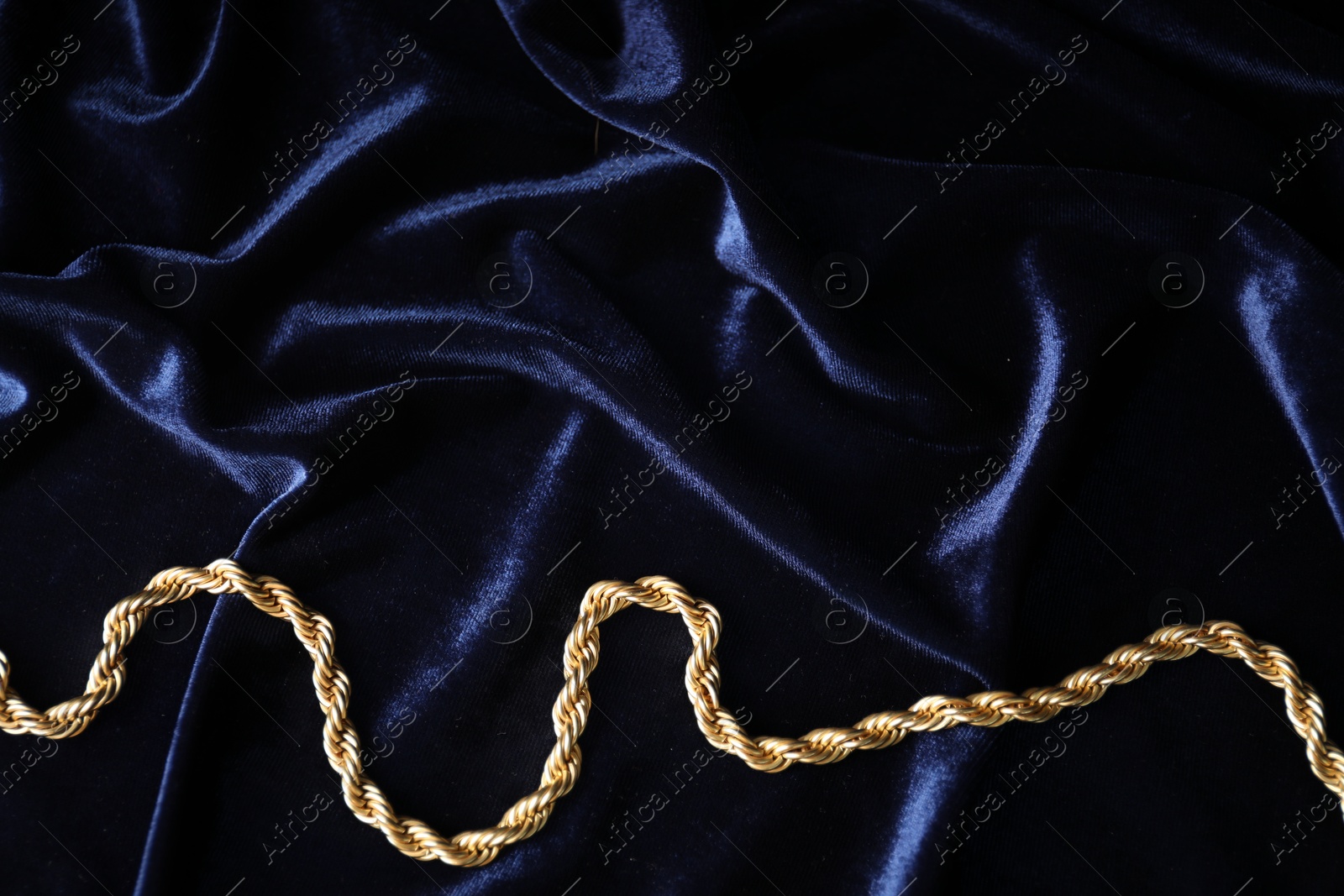 Photo of Stylish gold necklace on blue silk cloth, top view. Space for text