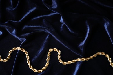 Photo of Stylish gold necklace on blue silk cloth, top view. Space for text