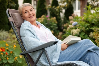 Photo of Senior woman with book in armchair outdoors