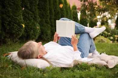 Photo of Senior woman reading book on blanket in garden