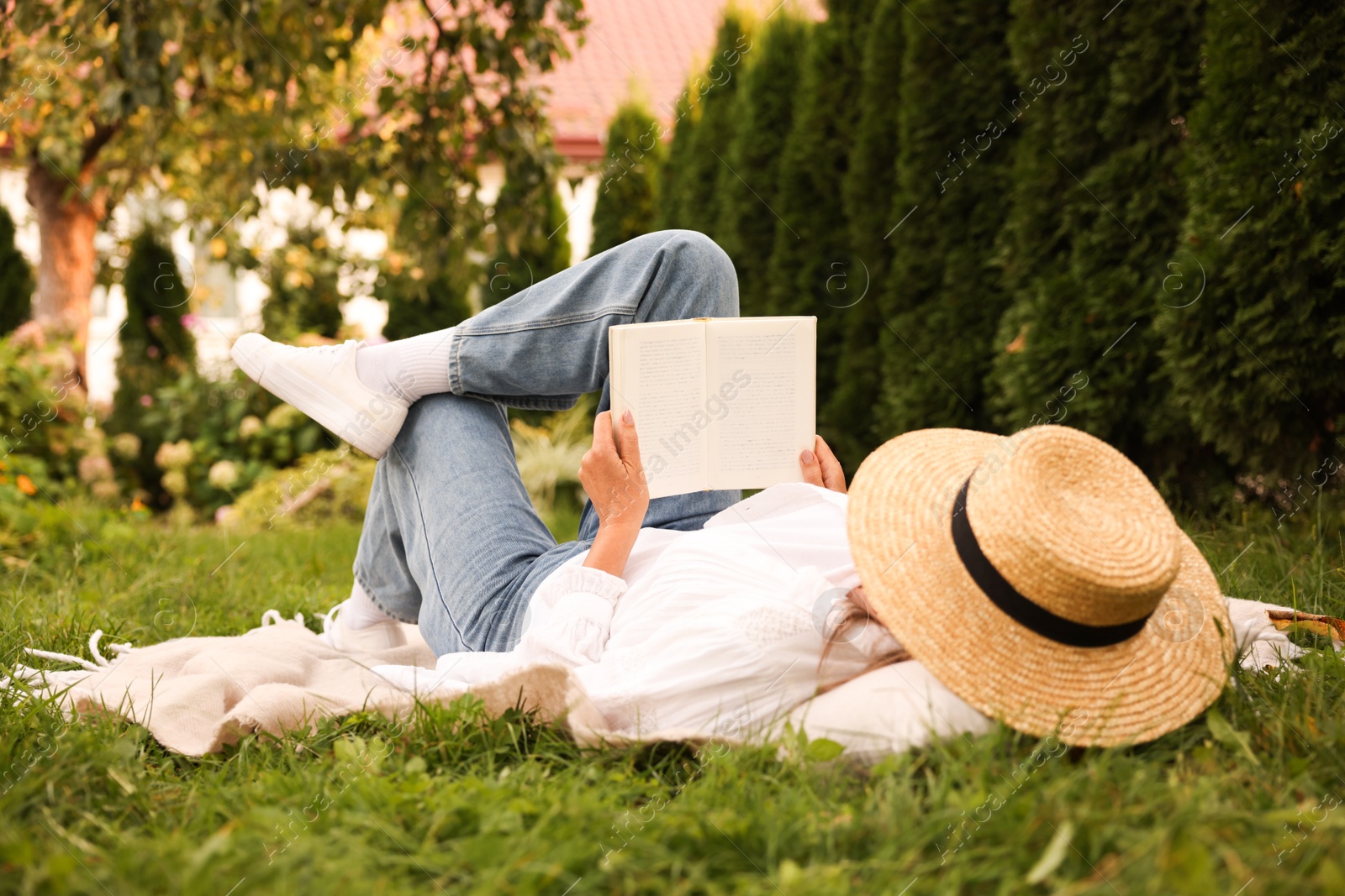Photo of Senior woman reading book on blanket in garden