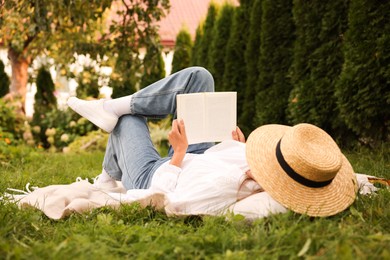 Photo of Senior woman reading book on blanket in garden