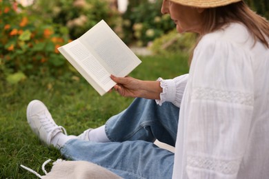 Photo of Senior woman reading book on blanket in garden, closeup