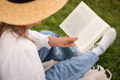 Photo of Senior woman reading book on blanket in garden, closeup