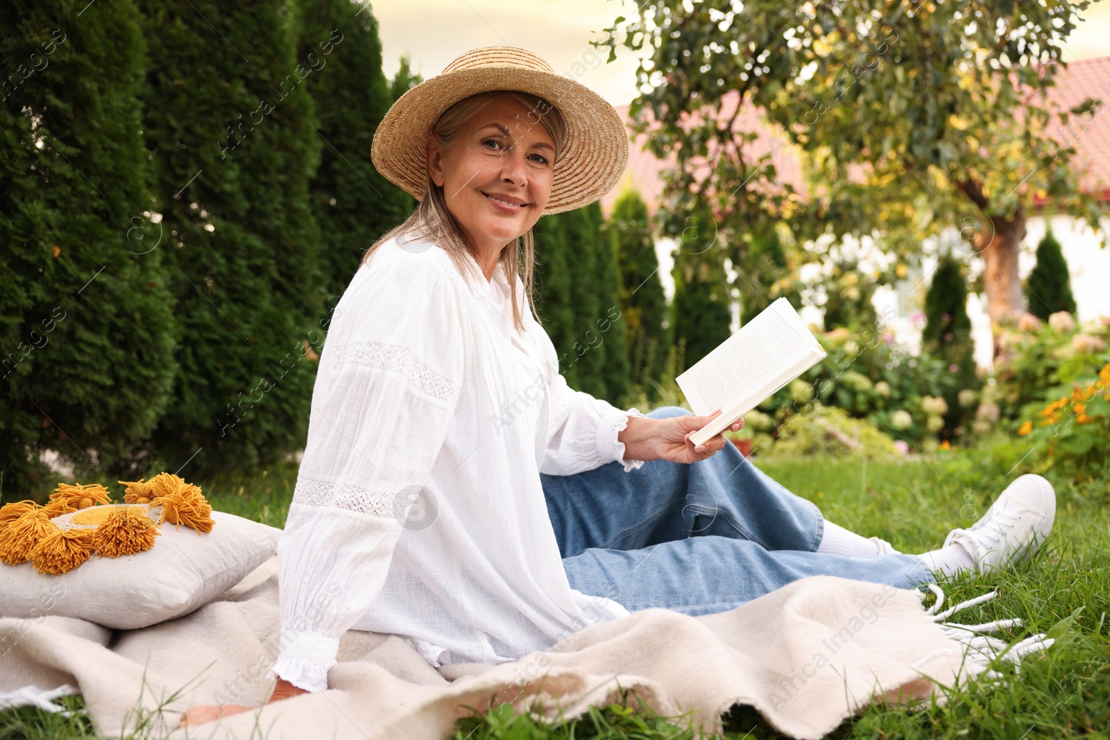 Photo of Senior woman reading book on blanket in garden