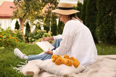 Photo of Senior woman reading book on blanket in garden