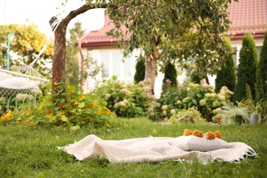 Photo of Blanket and pillow on green grass in garden