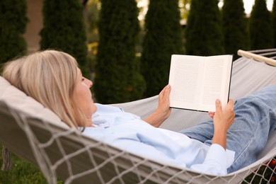 Photo of Senior woman reading book in hammock outdoors