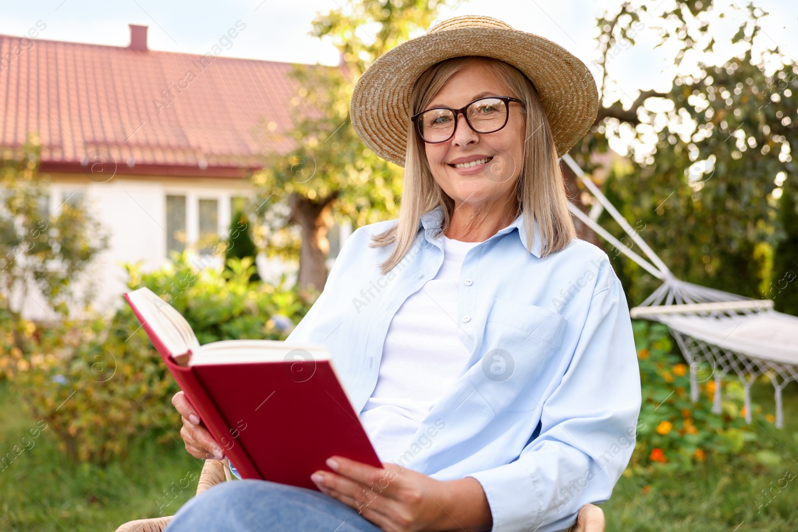 Photo of Senior woman reading book in armchair outdoors