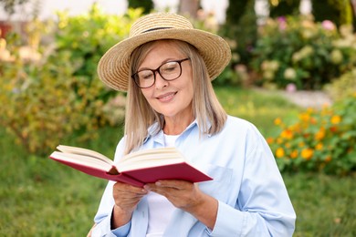 Photo of Senior woman in glasses reading book outdoors