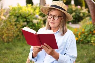 Photo of Senior woman in glasses reading book outdoors