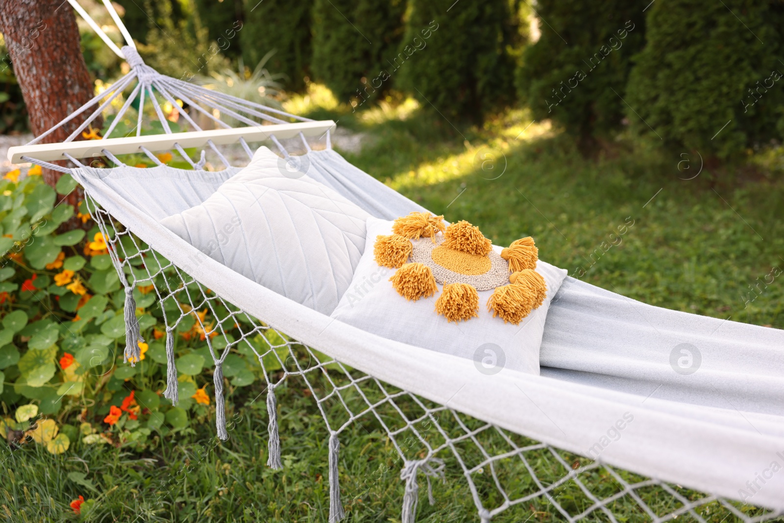Photo of Comfortable white hammock with pillows in garden