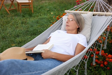 Photo of Senior woman with book resting in hammock outdoors