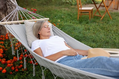 Photo of Senior woman resting in comfortable hammock outdoors