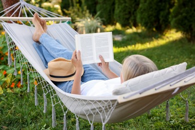 Photo of Senior woman reading book in hammock outdoors