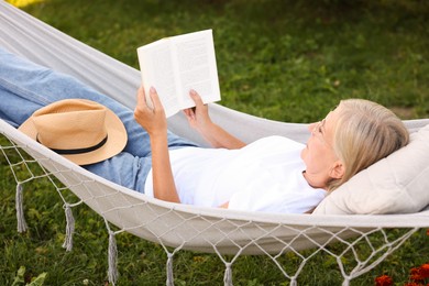 Photo of Senior woman reading book in hammock outdoors