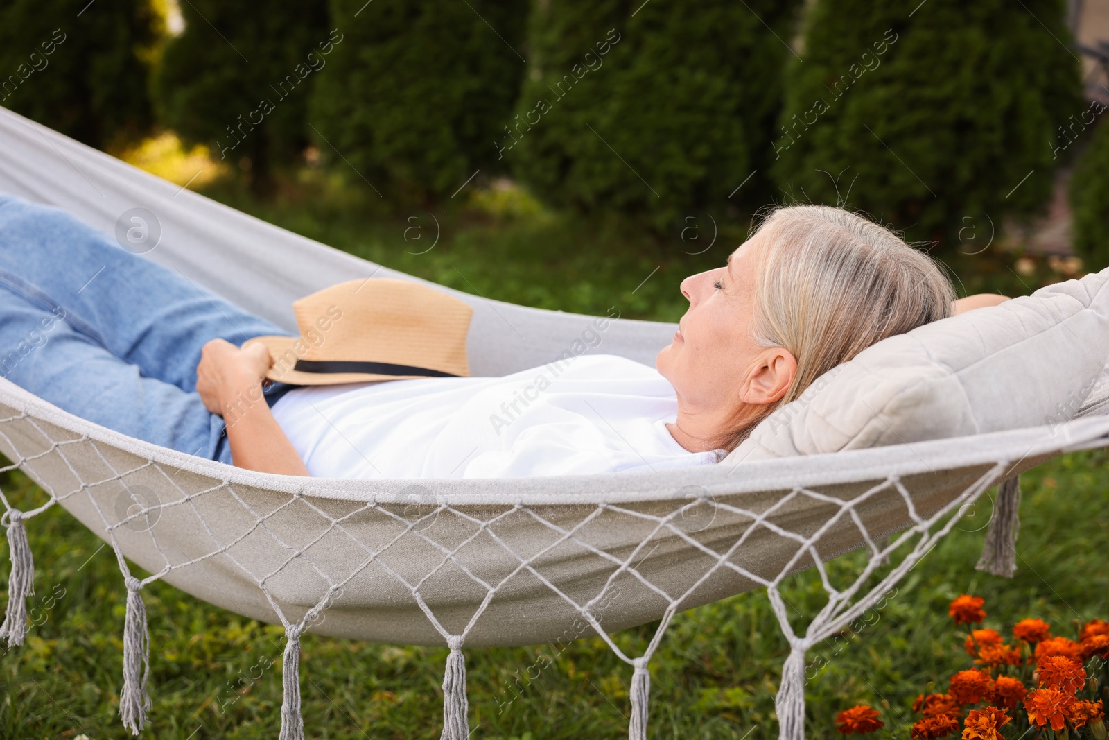 Photo of Senior woman resting in comfortable hammock outdoors