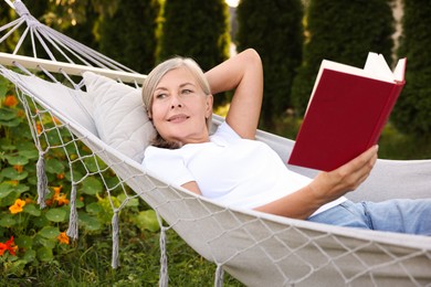 Photo of Senior woman with book resting in hammock outdoors