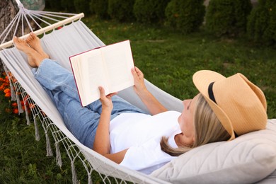 Photo of Senior woman reading book in hammock outdoors