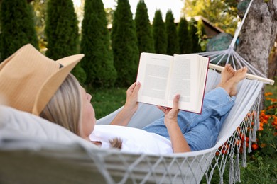 Photo of Senior woman reading book in hammock outdoors