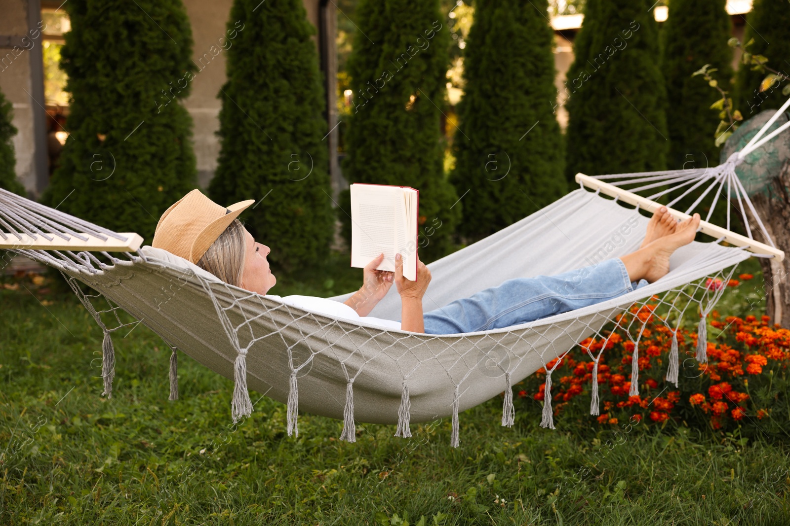 Photo of Senior woman reading book in hammock outdoors