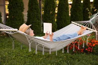 Photo of Senior woman reading book in hammock outdoors