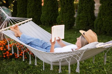 Photo of Senior woman reading book in hammock outdoors