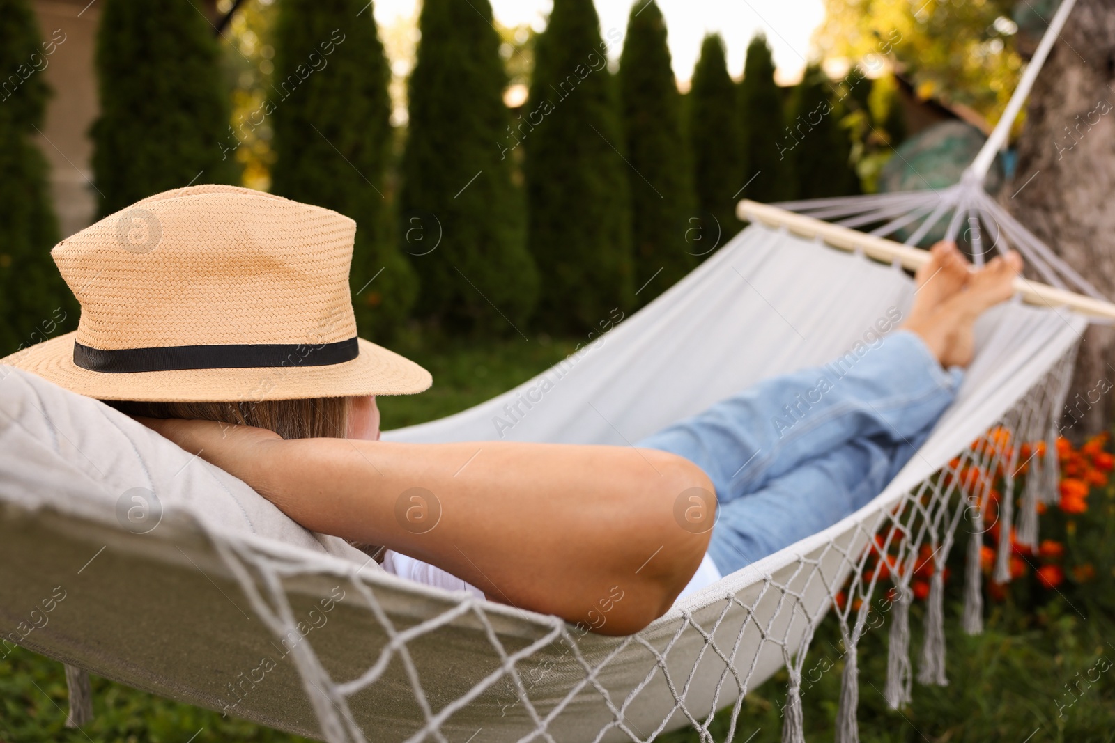 Photo of Senior woman in straw hat resting in hammock outdoors