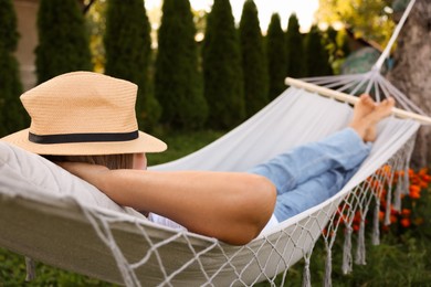 Photo of Senior woman in straw hat resting in hammock outdoors
