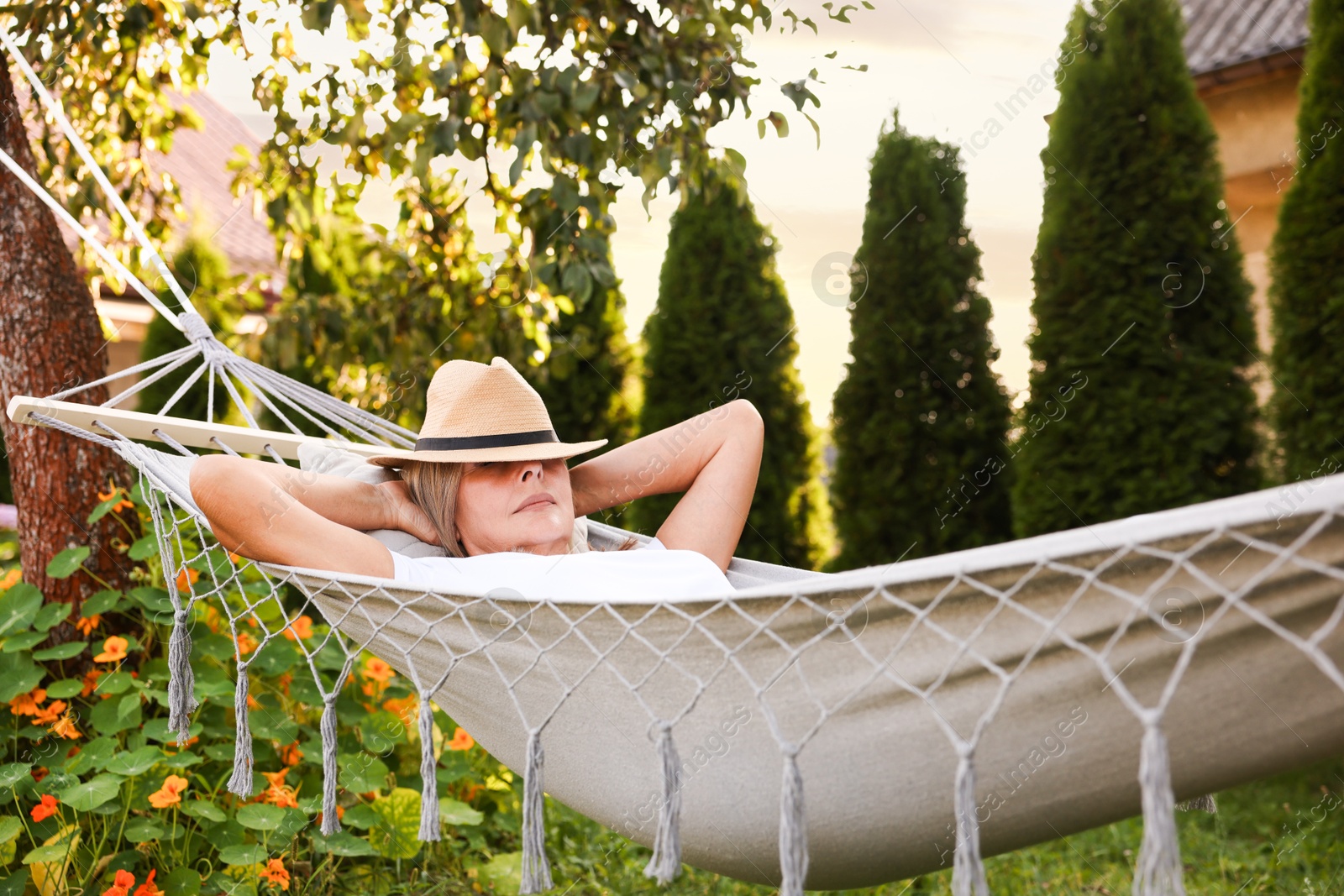Photo of Senior woman in straw hat resting in hammock outdoors
