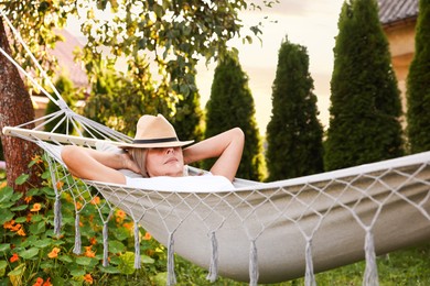 Photo of Senior woman in straw hat resting in hammock outdoors