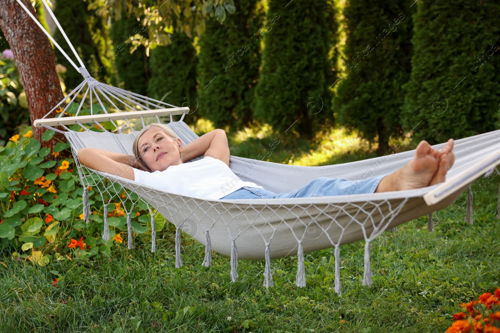 Photo of Senior woman resting in comfortable hammock outdoors