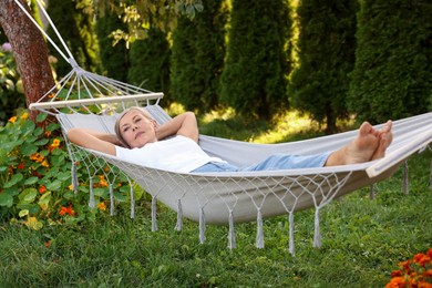 Photo of Senior woman resting in comfortable hammock outdoors