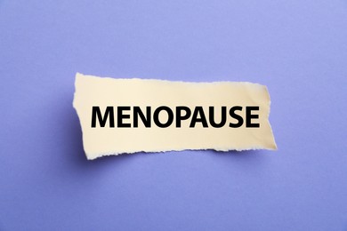 Photo of Paper with word Menopause on violet background, top view