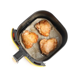Photo of Air fryer basket with chicken thighs isolated on white, top view
