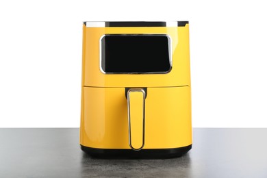Photo of Modern yellow air fryer on grey table against white background