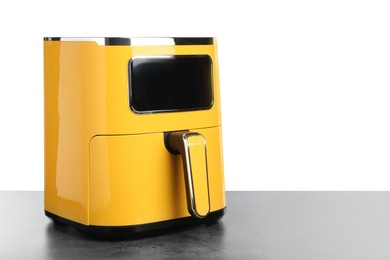 Photo of Modern yellow air fryer on grey table against white background
