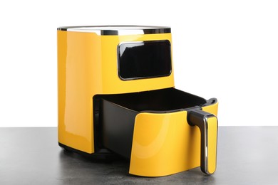 Photo of Modern yellow air fryer on grey table against white background