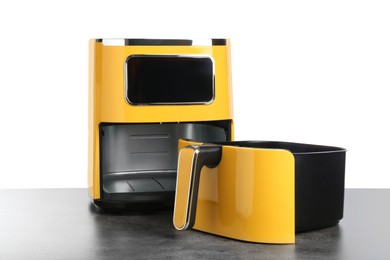 Photo of Modern yellow air fryer on grey table against white background