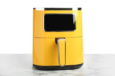 Photo of Modern yellow air fryer on marble table against white background